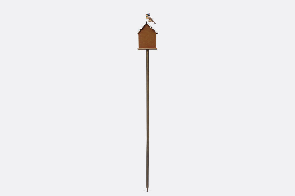 A holiday themed birdhouse with a bird wearing a knitted cap and scarf.