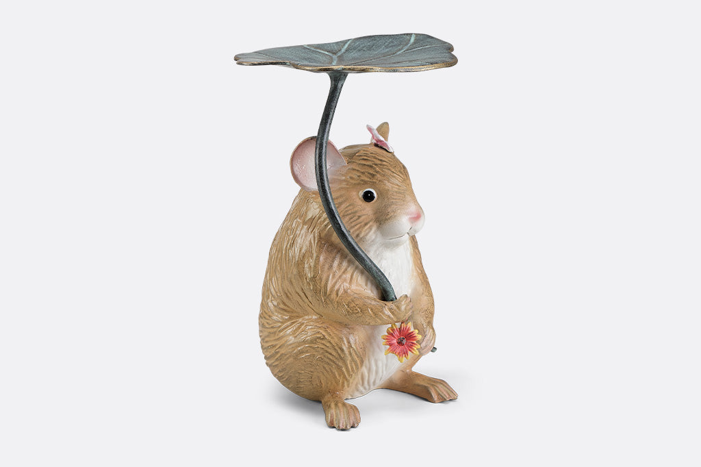A sculpture of a hamster holding a leaf and flower