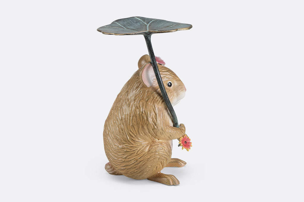 A sculpture of a hamster holding a leaf and flower