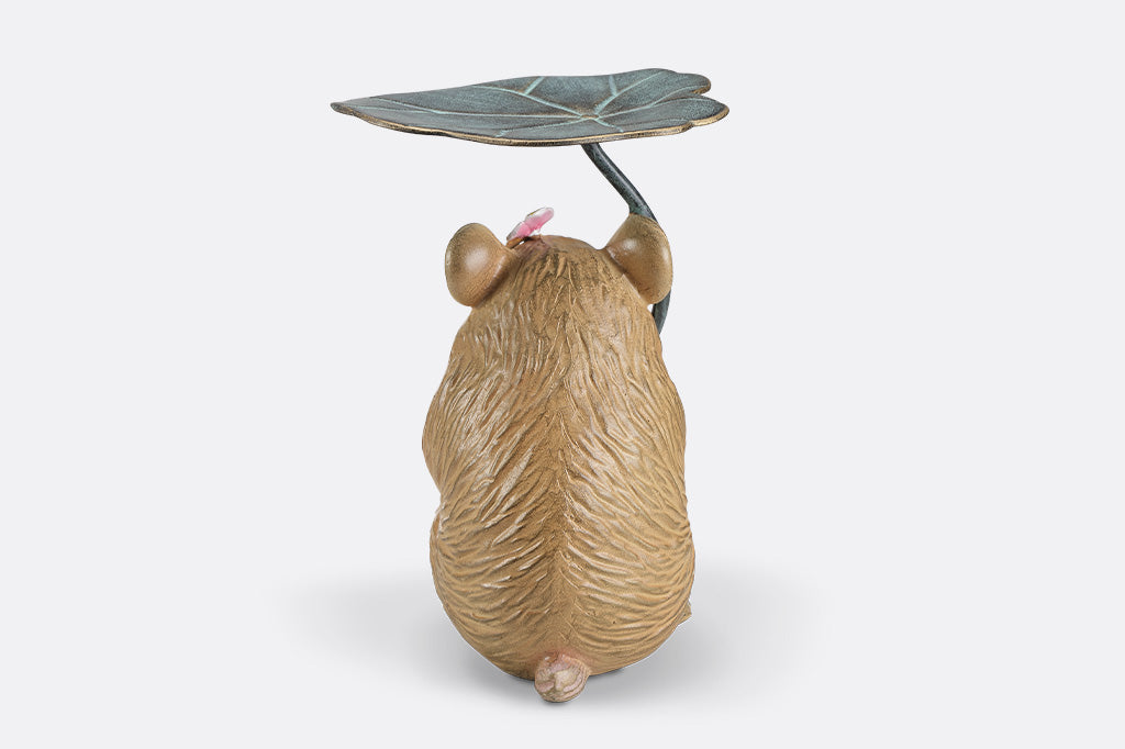 A sculpture of a hamster holding a leaf and flower