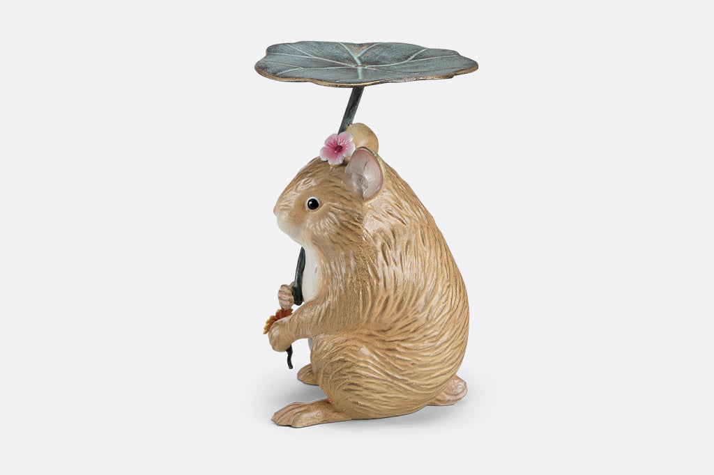 A sculpture of a hamster holding a leaf and flower