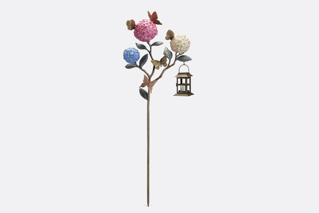 A garden stake lantern of 3 hydrangea flowers with a group of butterflies.