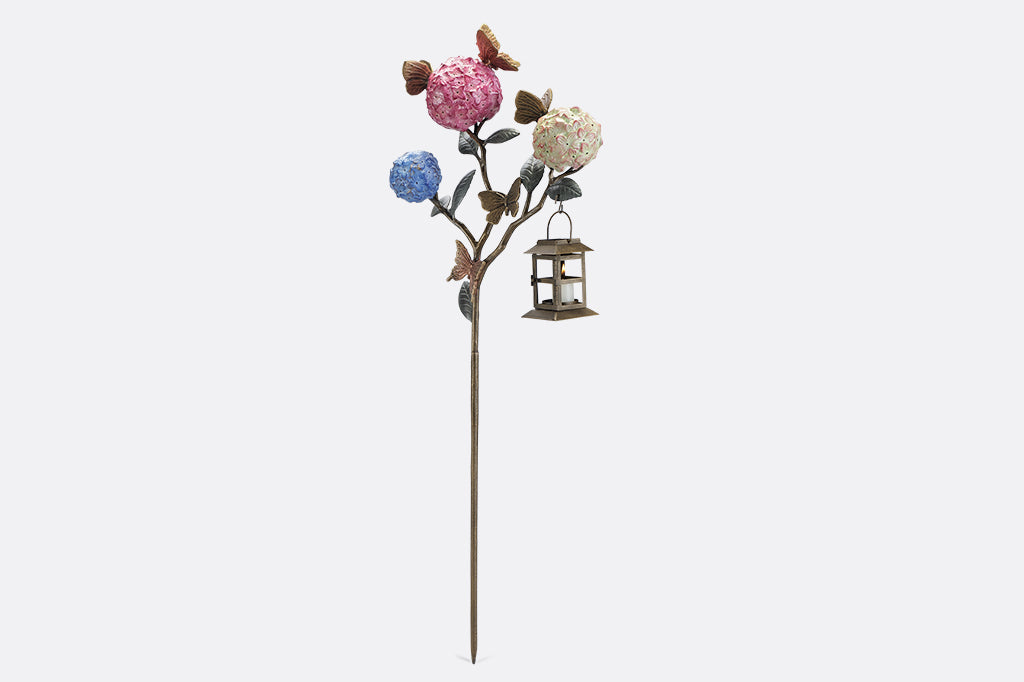 A garden stake lantern of 3 hydrangea flowers with a group of butterflies.