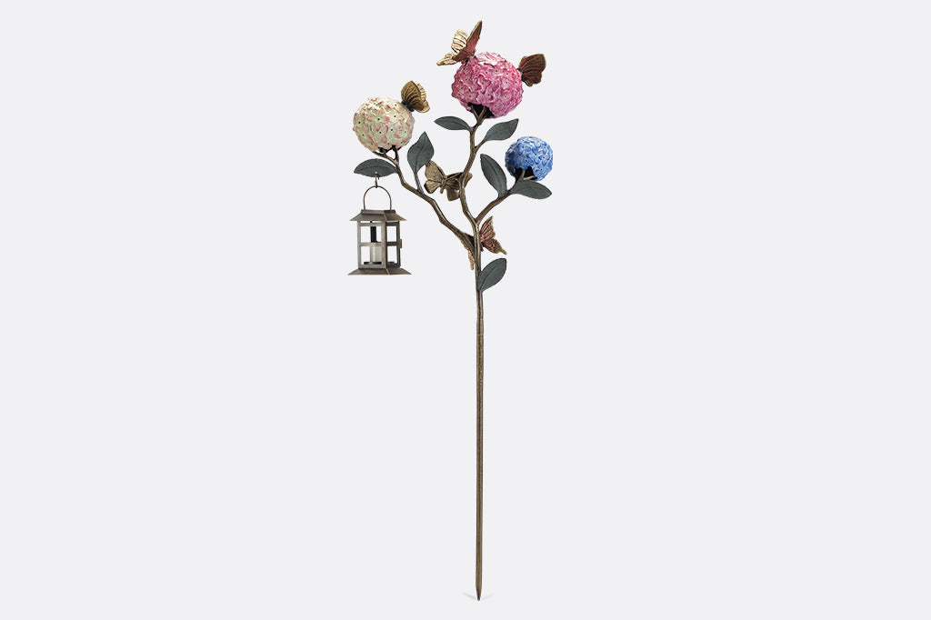 A garden stake lantern of 3 hydrangea flowers with a group of butterflies.