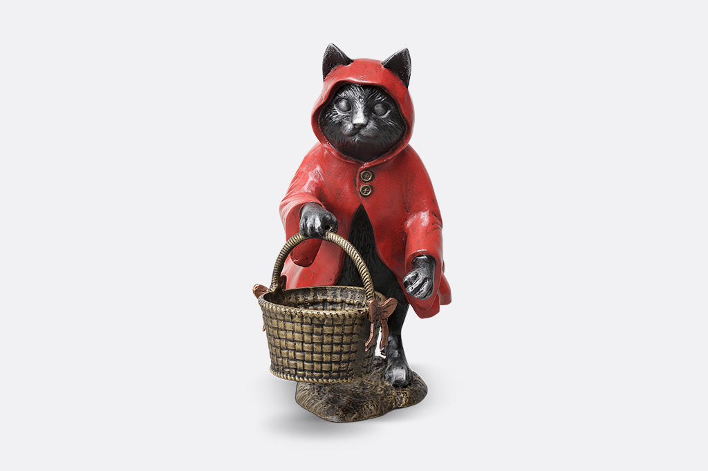 Cat figurine in a red hood holding a basket on a white background