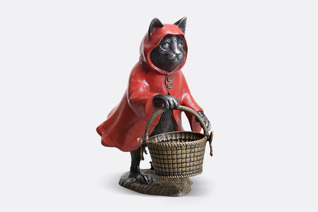Black cat figurine in a red hood with a basket on a white background
