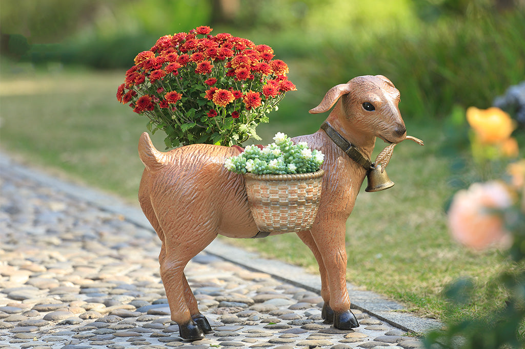 A planter sculpture of a goat with a bell carrying two baskets at his side.
