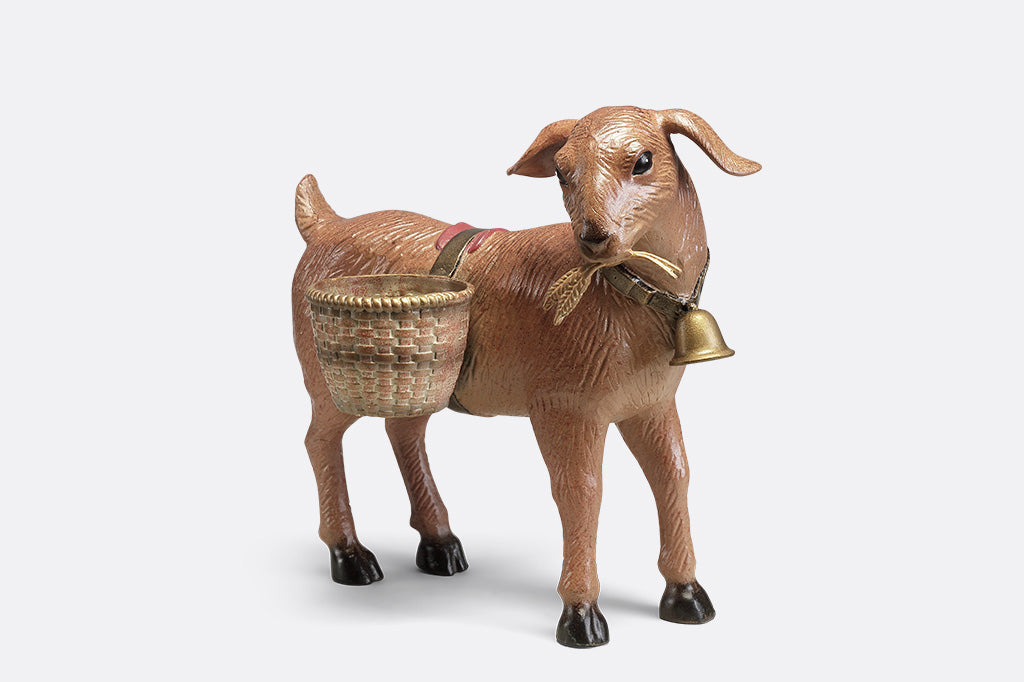 A planter sculpture of a goat with a bell carrying two baskets at his side.