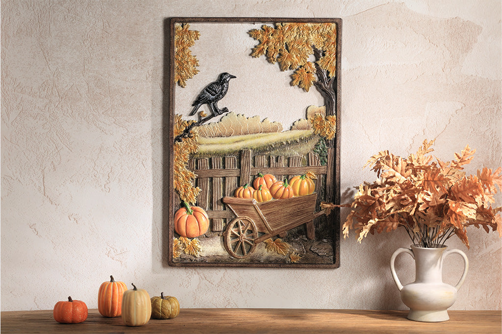 Decorative wall art with pumpkins and a wheelbarrow on a neutral wall.