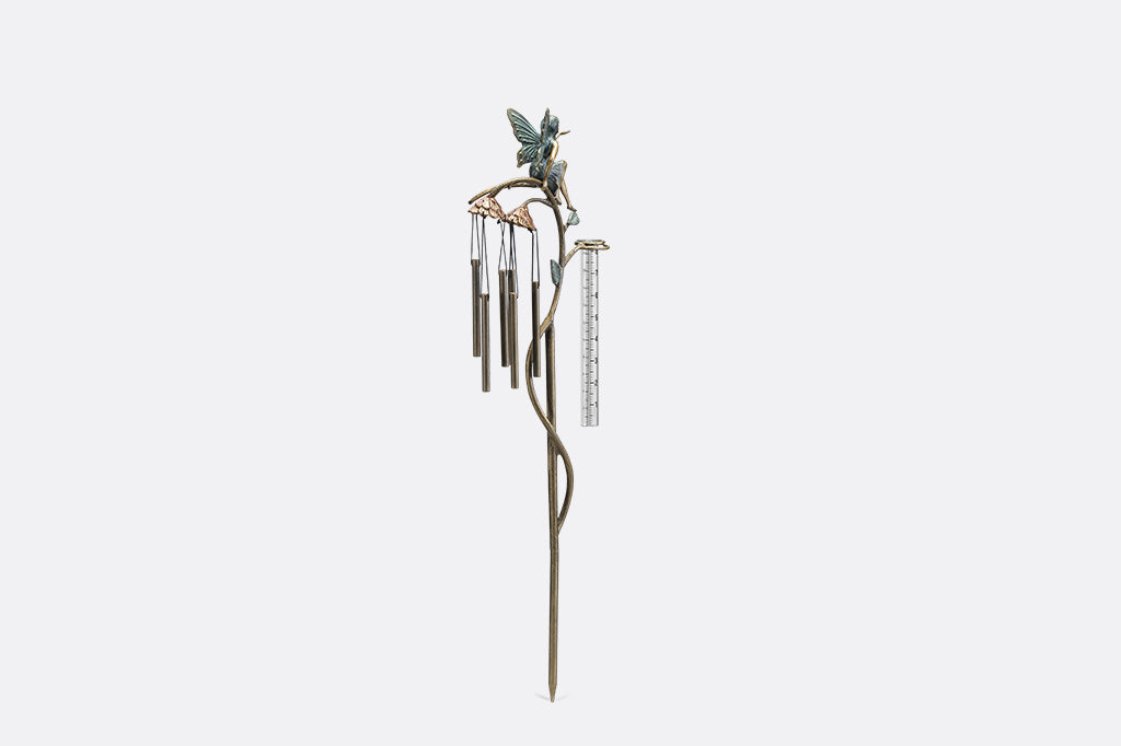A staked raincatcher and windchime of a fairy sitting on flowers.