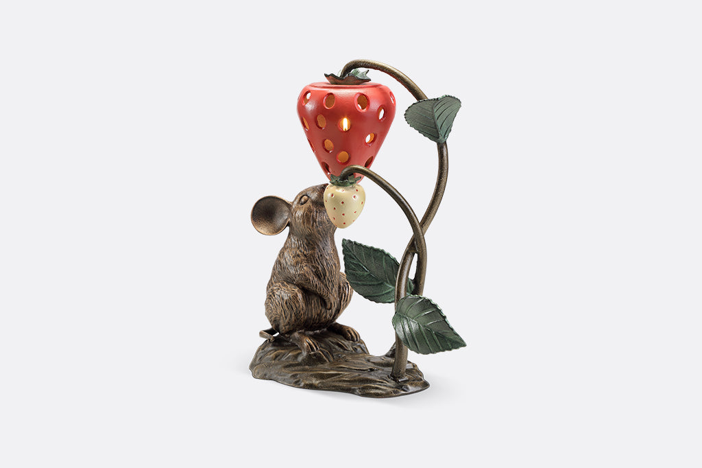 A sculpture of a mouse looking up at a strawberry shaped lantern.
