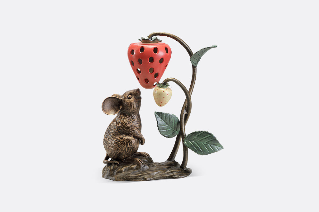 A sculpture of a mouse looking up at a strawberry shaped lantern.