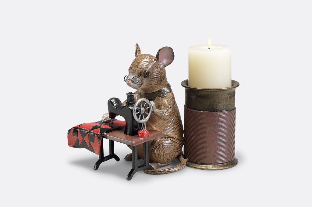 A candleholder of a mouse at a sewing machine stitching fabric.