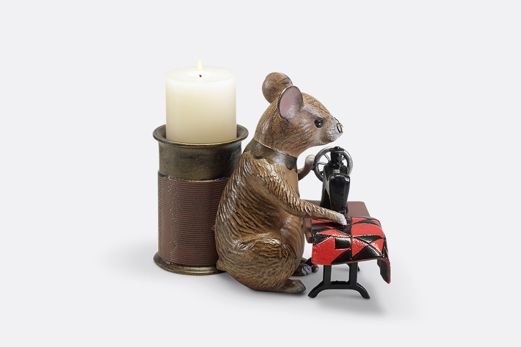 A candleholder of a mouse at a sewing machine stitching fabric.