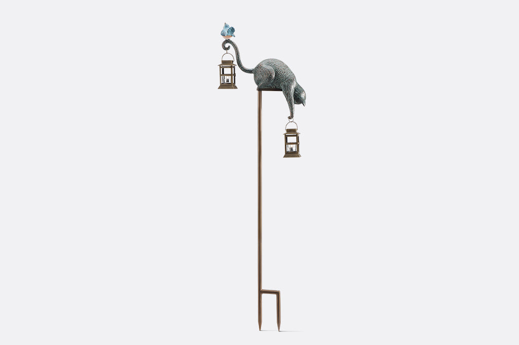 Decorative garden stake with cat and bird design on a white background