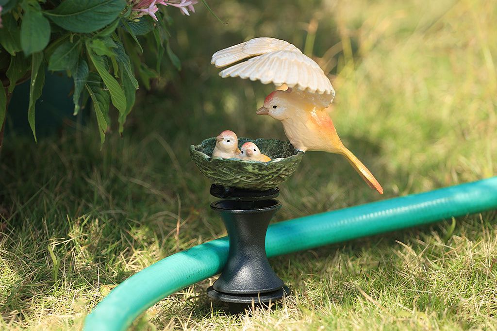 A hose guard sculpture of a mother bird sheltering her babies in their nest.