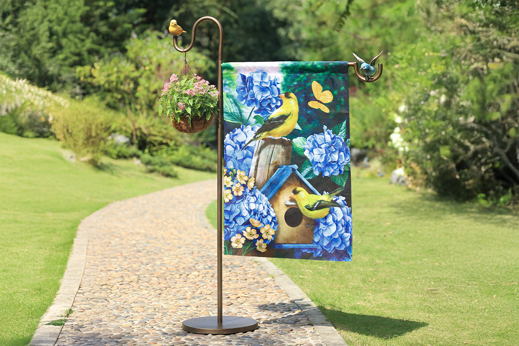 A flag stand with two birds and a flag with a birdhouse.