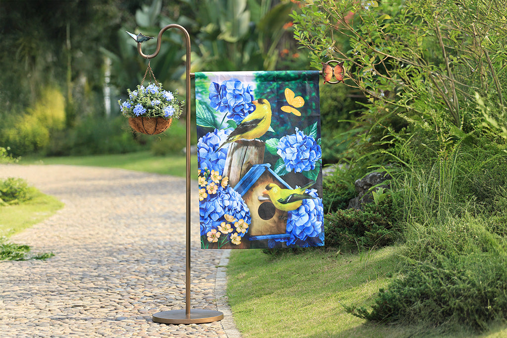 A flag stand with two butterflies and a flag of two birds and a birdhouse
