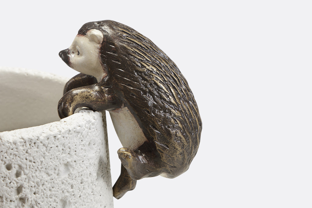 Pot hanging sculptures of two hedgehogs climbing.