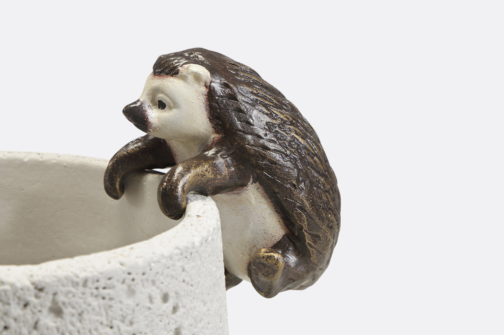 Pot hanging sculptures of two hedgehogs climbing.