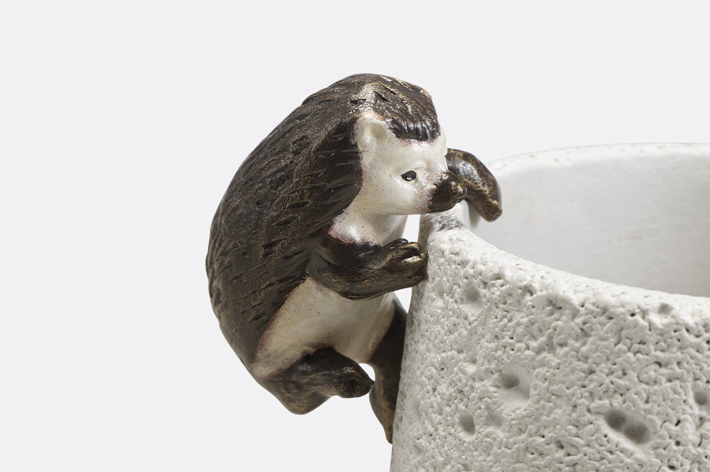 Pot hanging sculptures of two hedgehogs climbing.
