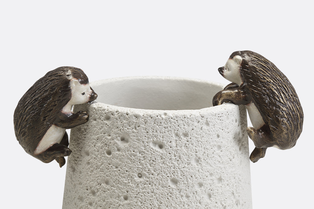 Pot hanging sculptures of two hedgehogs climbing.