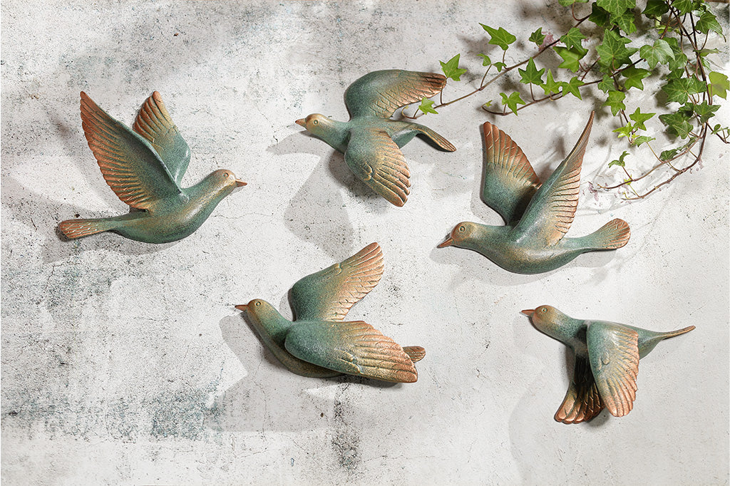Set of 5decorative birds on a textured wall with greenery.