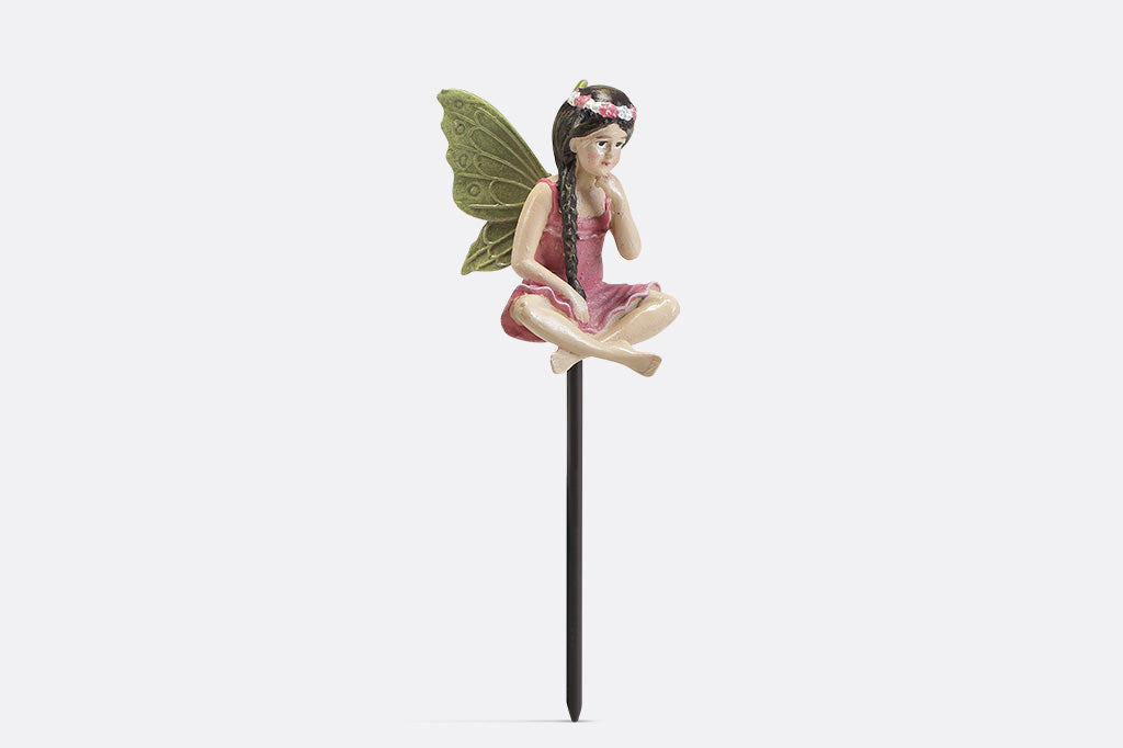 A plant pot stake sculpture of a fairy wearing pink.
