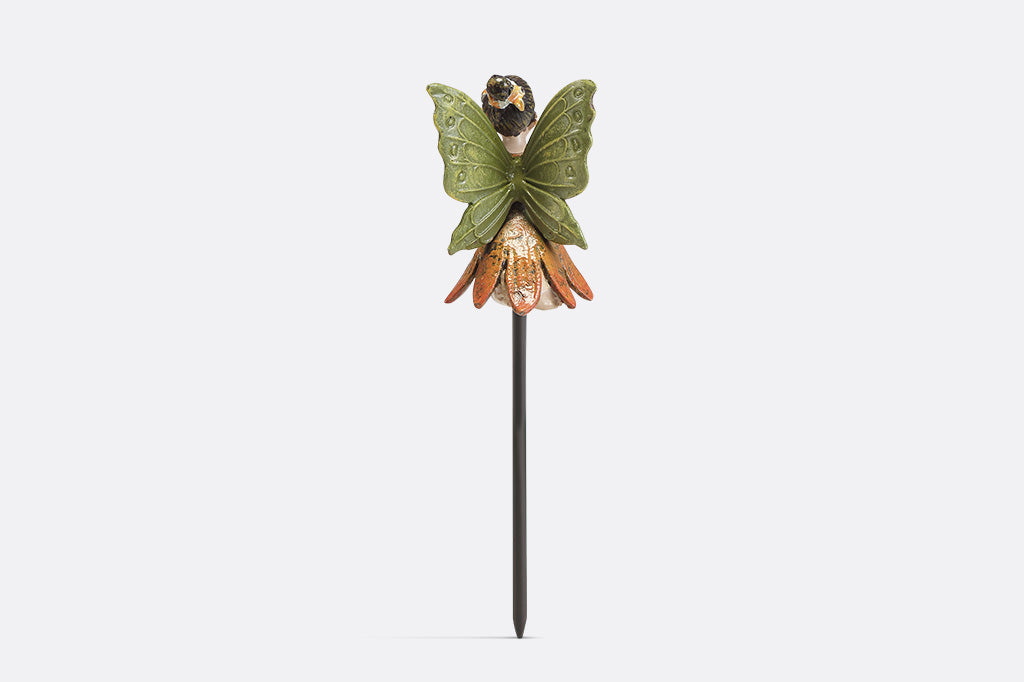 A plant pot stake sculpture of a fairy wearing orange and holding a flower.