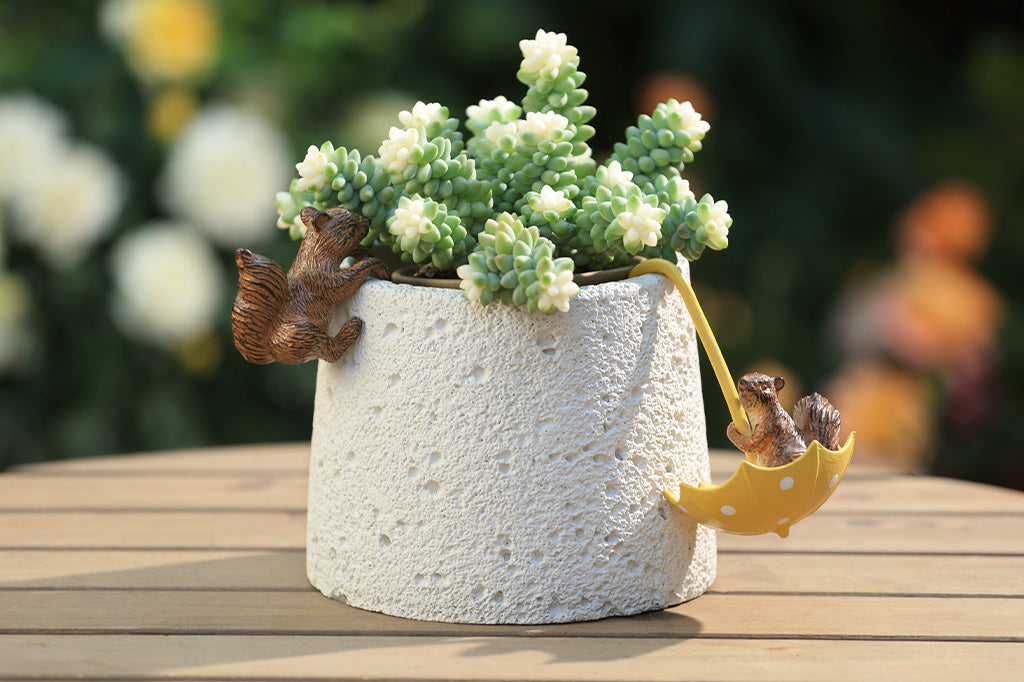 Pot hanging sculpture of a squirrel climbing and a squirrel playing with an umbrella.