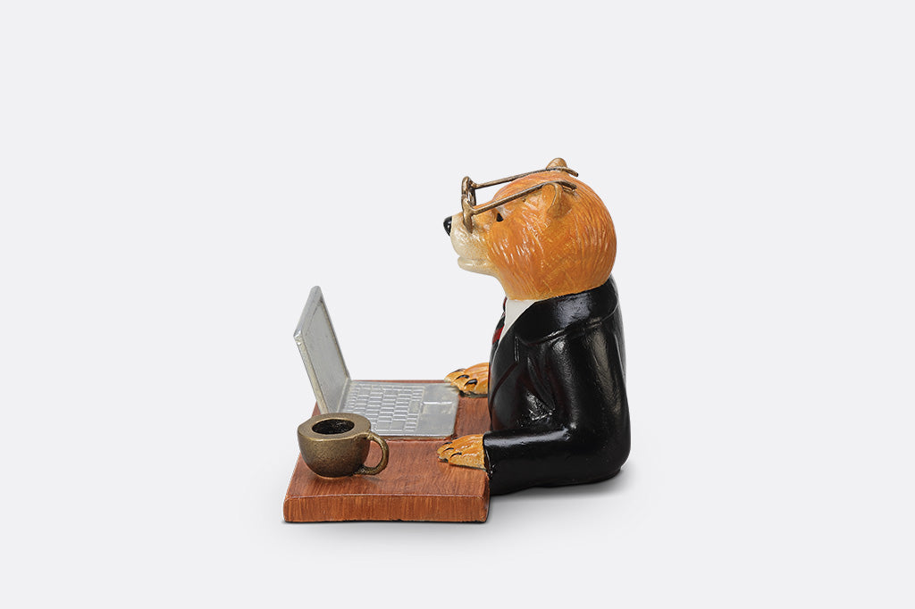 A sculpture of a bear wearing a suit on his Fishbook Pro laptop with a mug.