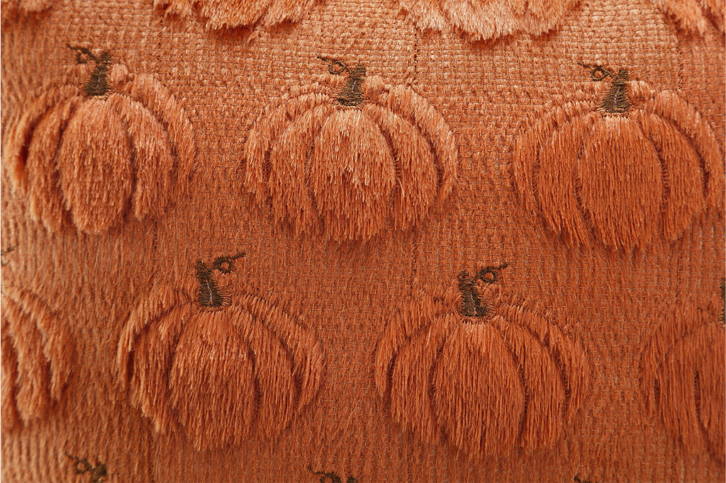 Textured fabric with embroidered pumpkins on a brown background