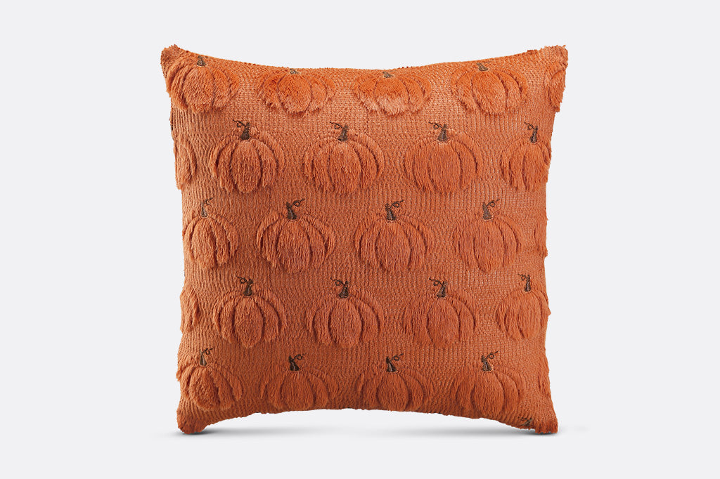 Orange pillow with pumpkin pattern on a white background