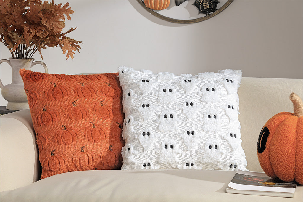 Two decorative pillows on a couch with pumpkins and a mirror in the background.