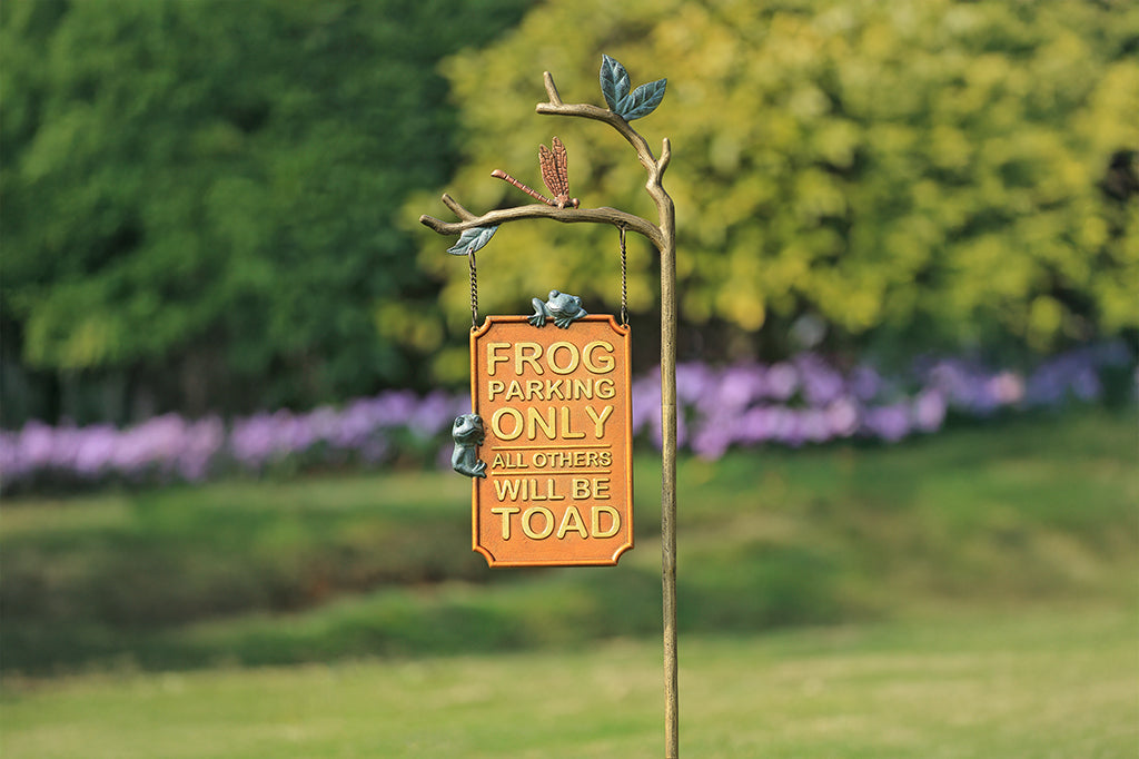 A staked sign with frogs, dragonflies, and branches, with a sign that reads "Frog Parking Only. All others will be toad."