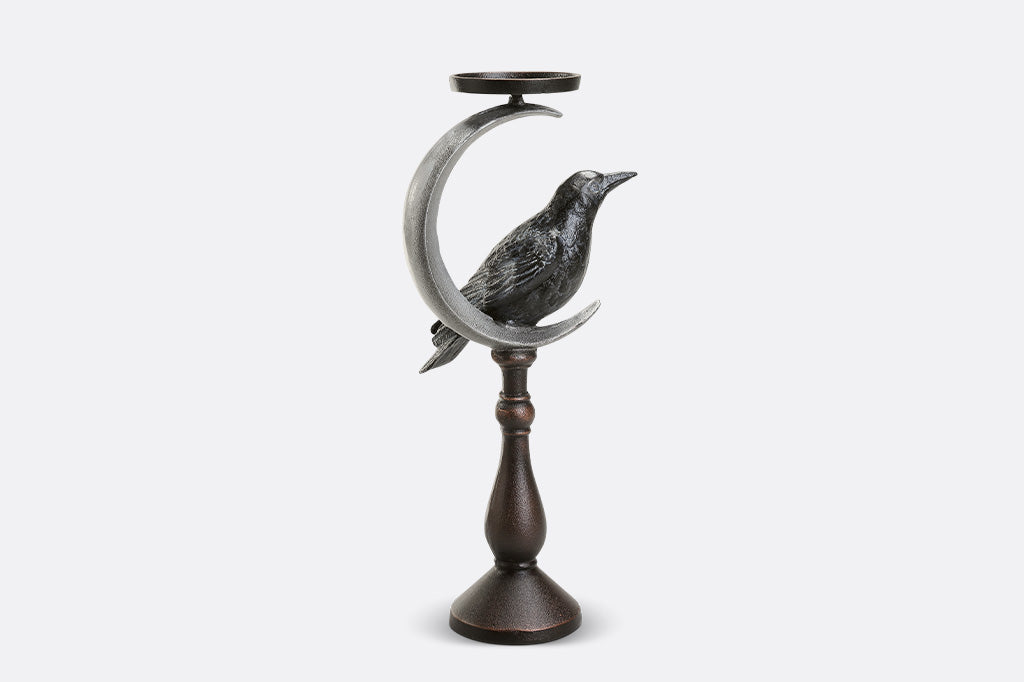 Decorative candle holder with a bird and crescent moon design on a white background