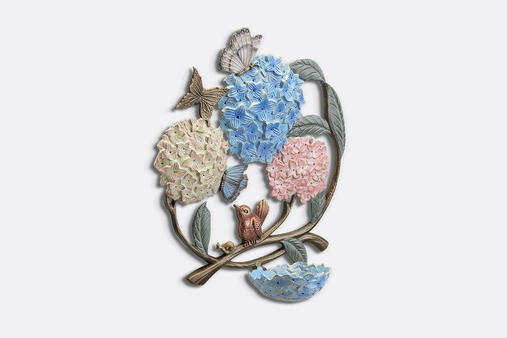 A round, wall mounted bird feeder with details of hydrangeas, leaves, birds, butterflies, and snails.