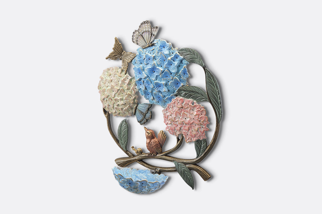 A round, wall mounted bird feeder with details of hydrangeas, leaves, birds, butterflies, and snails.