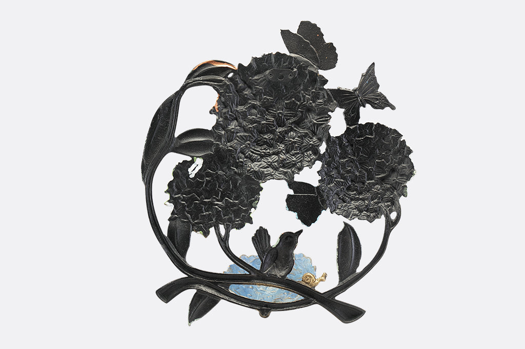 A round, wall mounted bird feeder with details of hydrangeas, leaves, birds, butterflies, and snails.