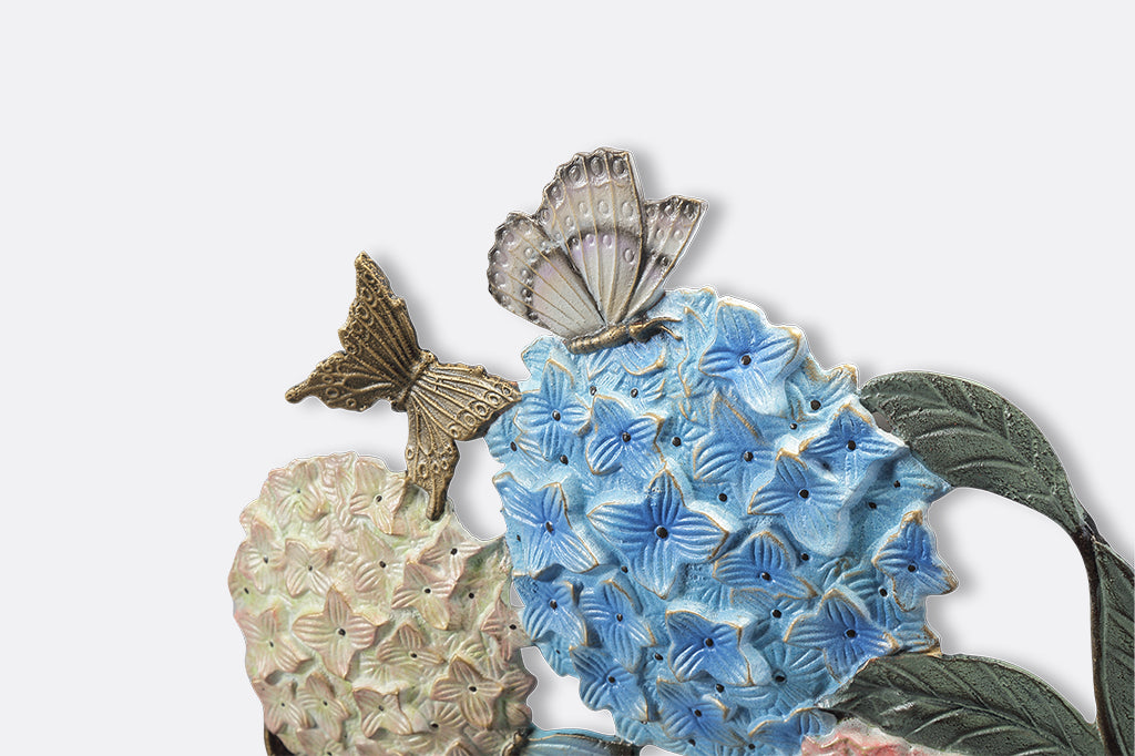 A round, wall mounted bird feeder with details of hydrangeas, leaves, birds, butterflies, and snails.