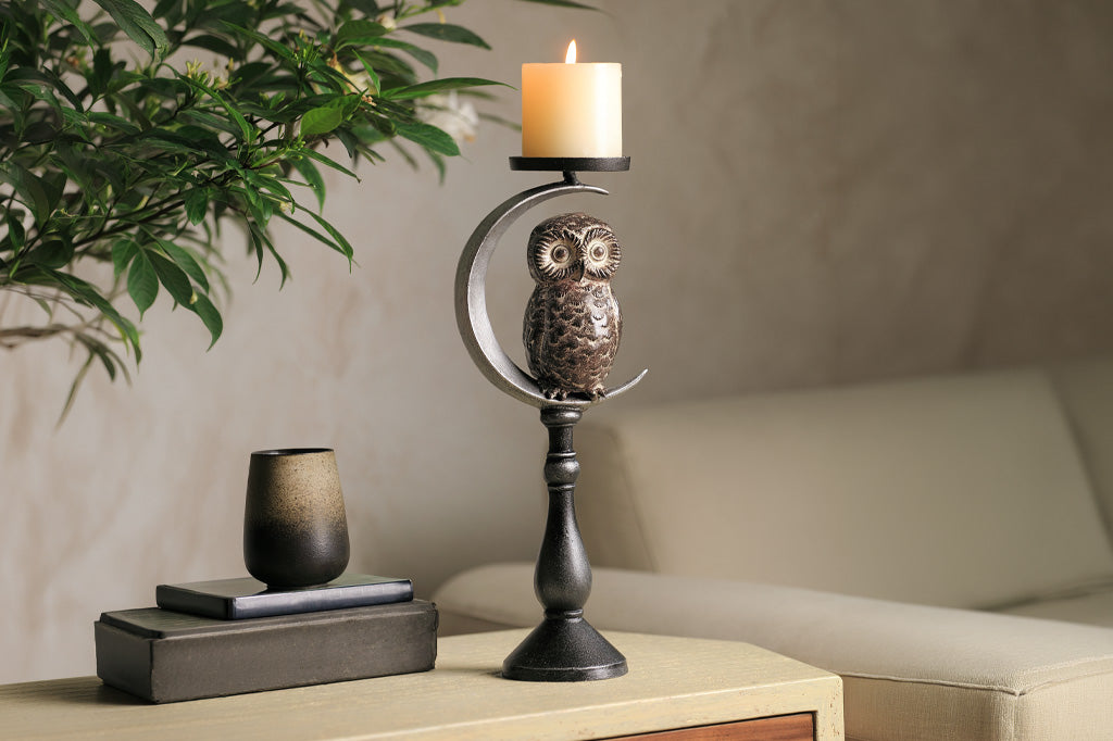 Decorative owl candle holder with a candle on a table in a home setting.