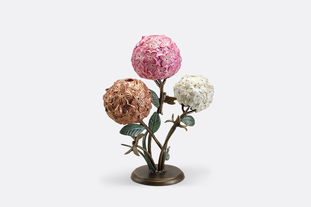 A candleholder featuring 3 hydrangea blossoms with dragonflies and a snail.