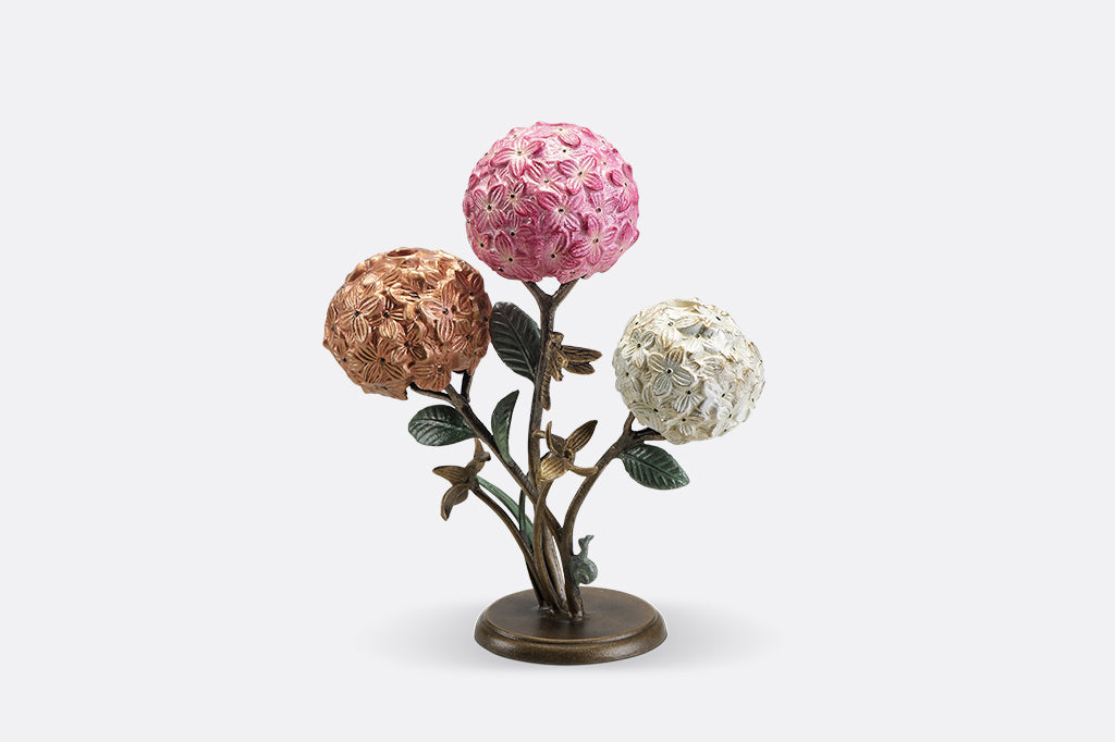 A candleholder featuring 3 hydrangea blossoms with dragonflies and a snail.