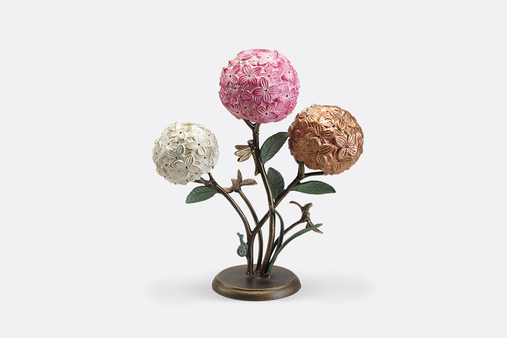 A candleholder featuring 3 hydrangea blossoms with dragonflies and a snail.