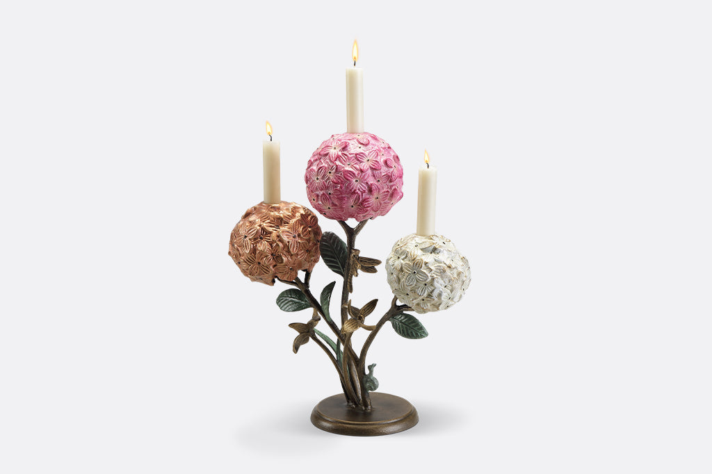 A candleholder featuring 3 hydrangea blossoms with dragonflies and a snail.