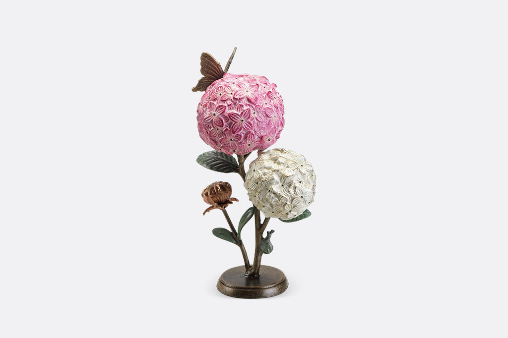 A single taper candle candle holder with two blooming hydrangeas, a butterfly, and a snail.