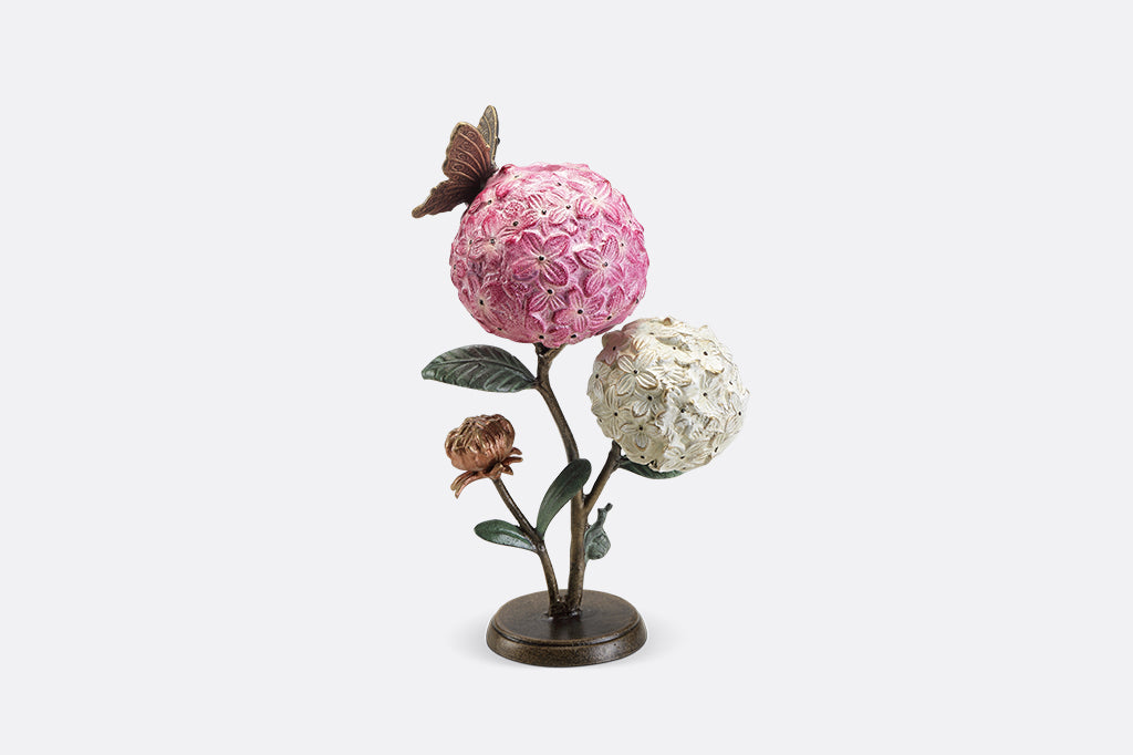 A single taper candle candle holder with two blooming hydrangeas, a butterfly, and a snail.