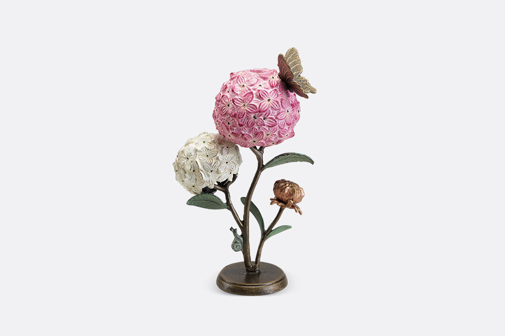 A single taper candle candle holder with two blooming hydrangeas, a butterfly, and a snail.