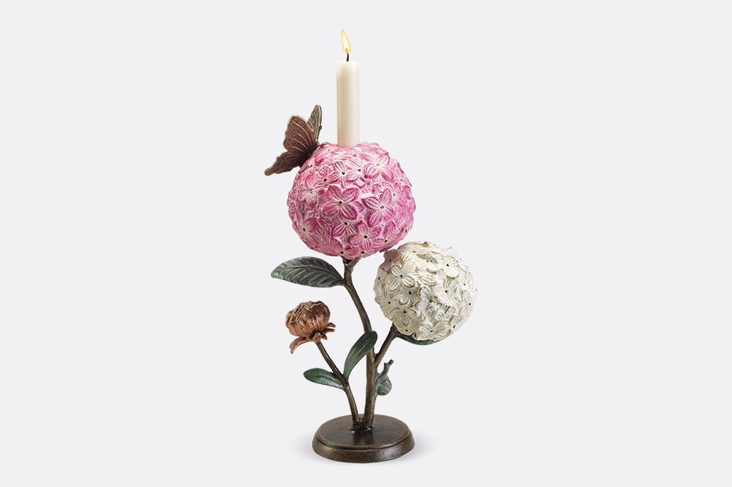 A single taper candle candle holder with two blooming hydrangeas, a butterfly, and a snail.