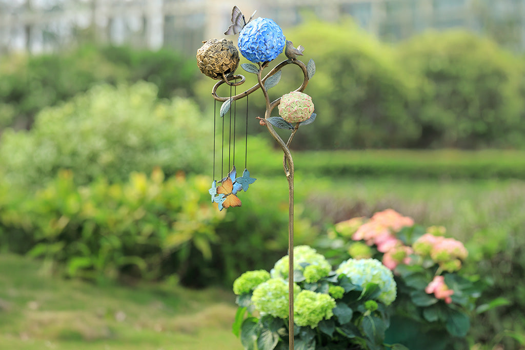 Decorative garden stake with colorful balls and butterflies in a garden setting